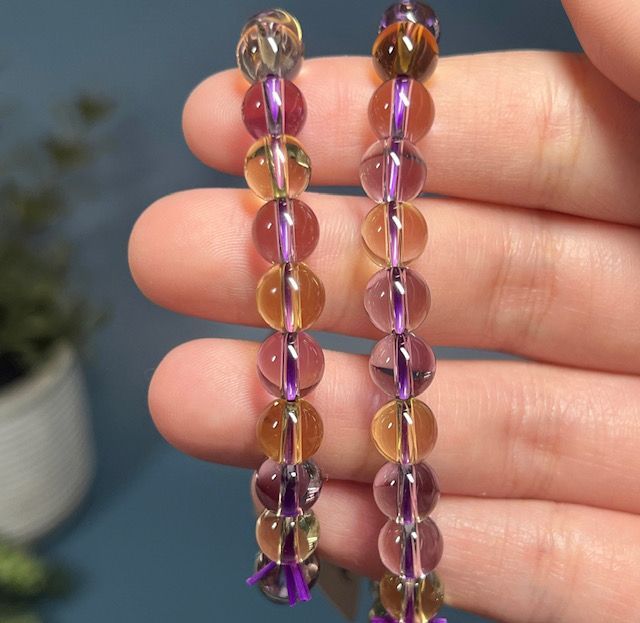 A person is holding a string of purple and brown beads