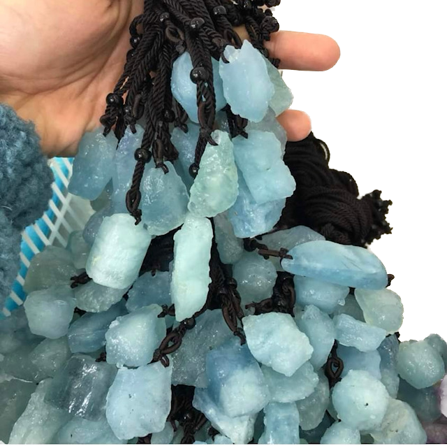 A person is holding a string of blue beads