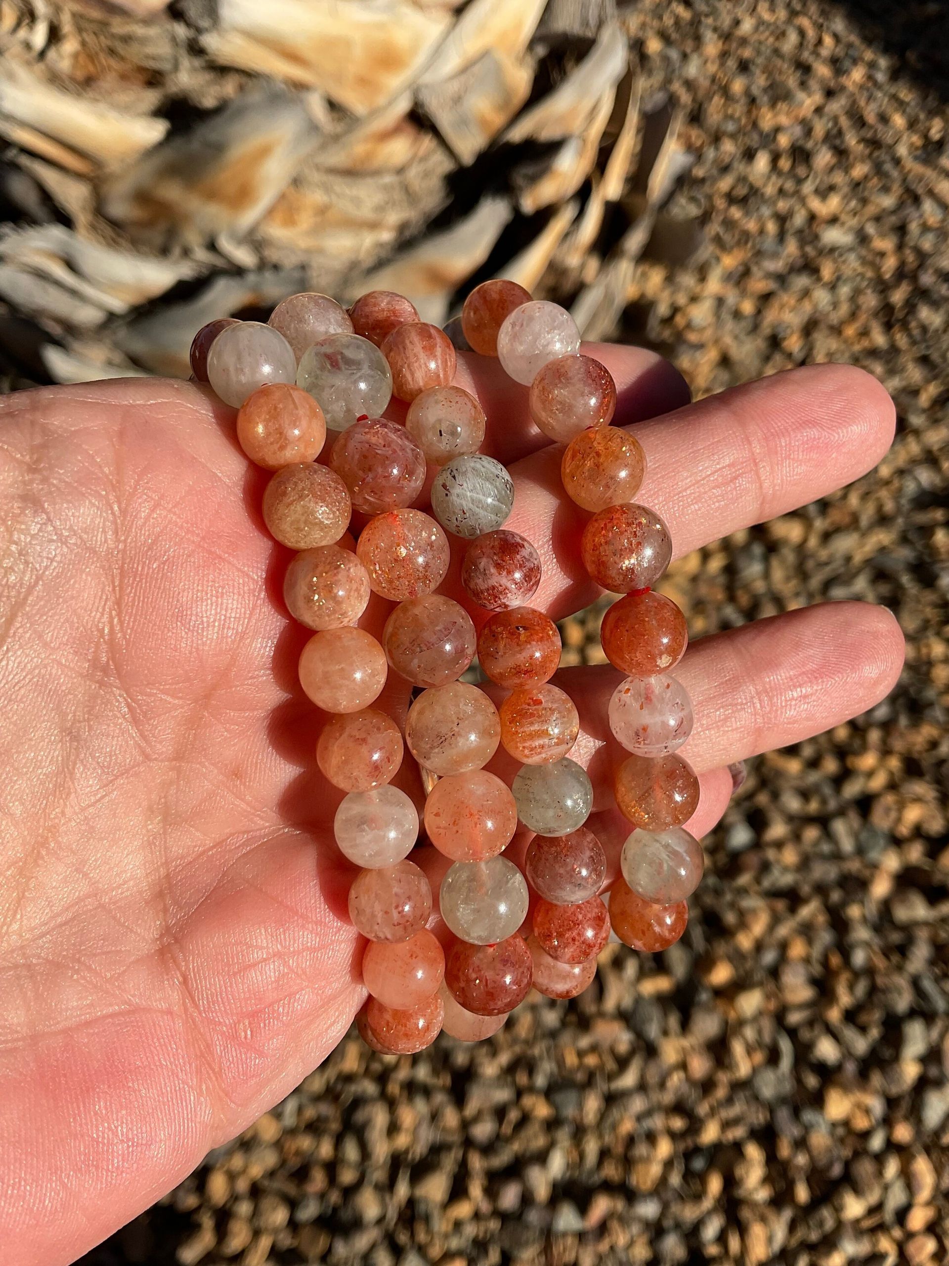A bracelet made of red and clear beads is sitting on a wooden table.