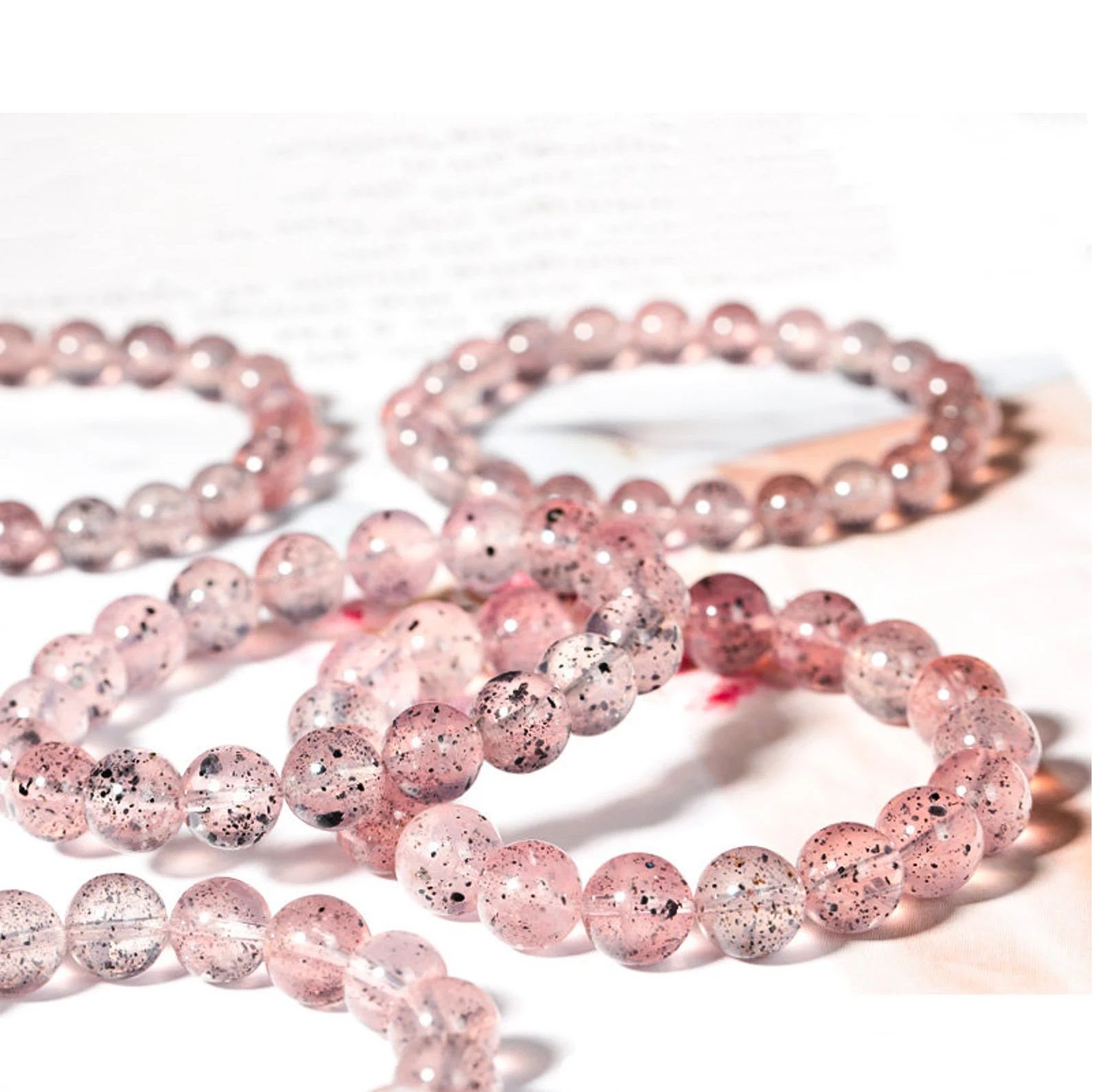 A bracelet made of pink and clear beads is sitting on a concrete surface.