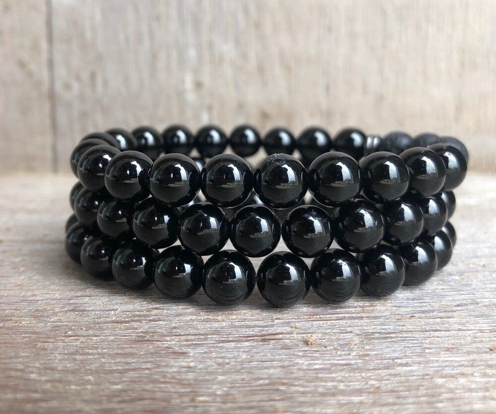 A bracelet made of black beads is sitting on a wooden table.