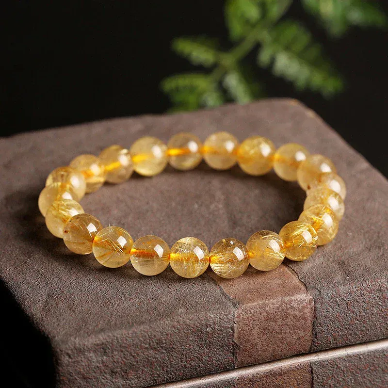 A bracelet made of yellow beads is sitting on top of a brick box.