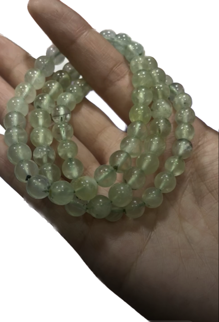 A person is holding a string of green beads in their hand