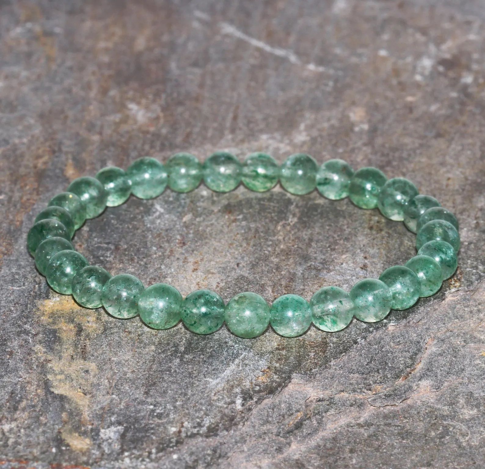 A bracelet made of green beads on a white surface.