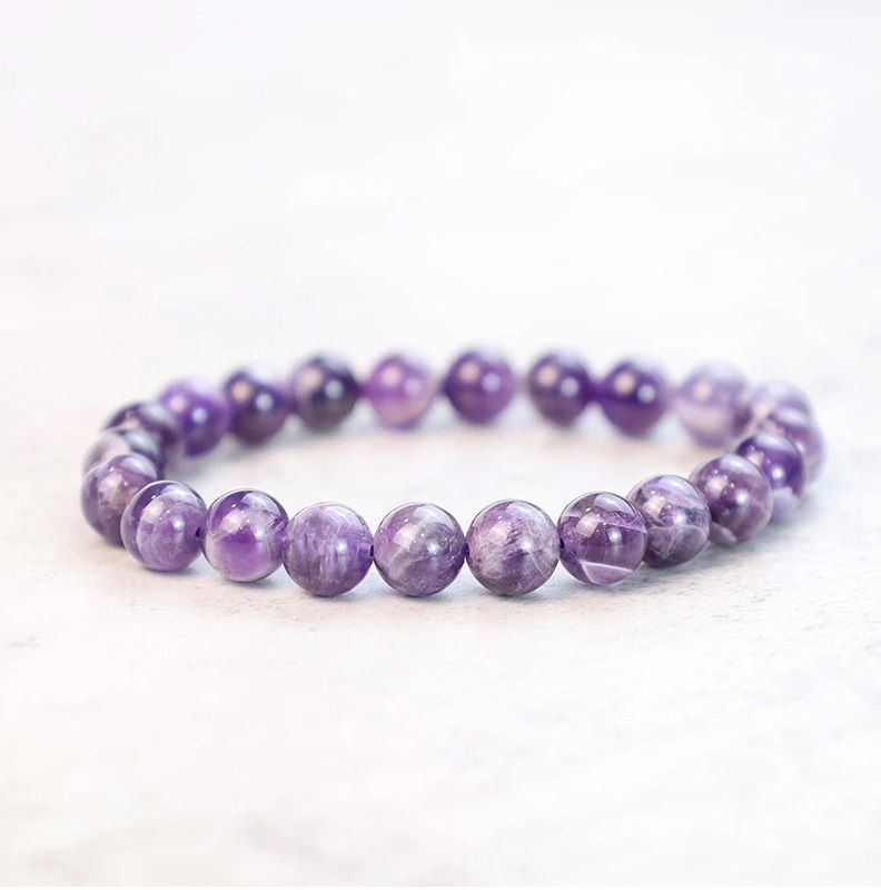 A bracelet with purple beads on a white surface.