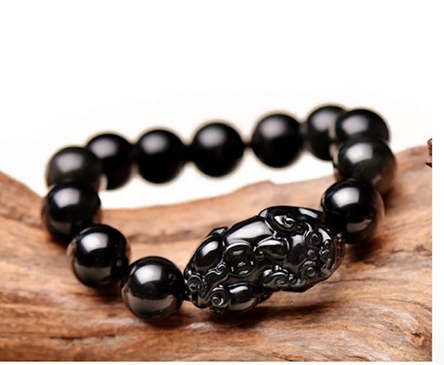 A bracelet made of black beads is sitting on a piece of wood.