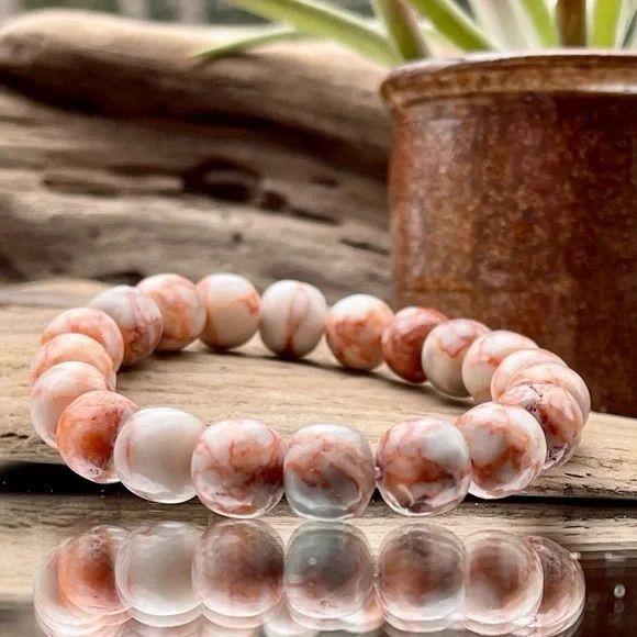 A bracelet is sitting on a wooden table next to a potted plant.