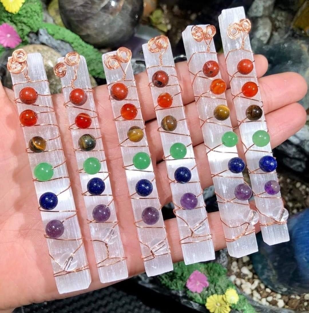 A person is holding a row of crystals with colored beads on them.