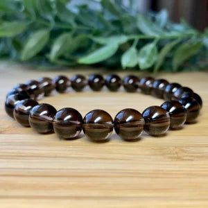 A bracelet made of brown beads is sitting on a wooden table.