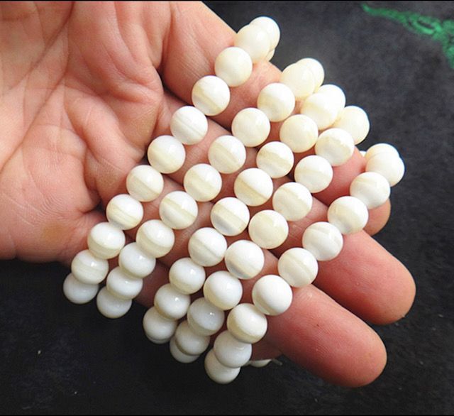 A person is holding a string of white beads in their hand