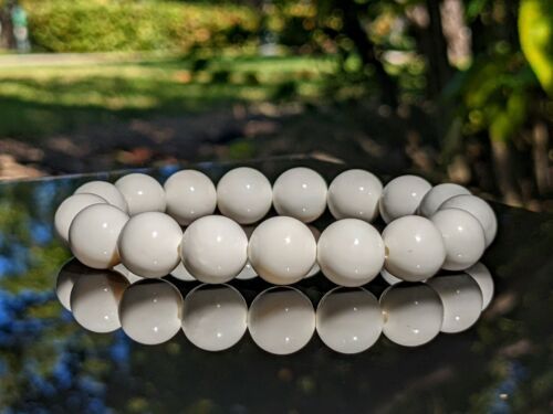 A person is holding a string of white beads in their hand