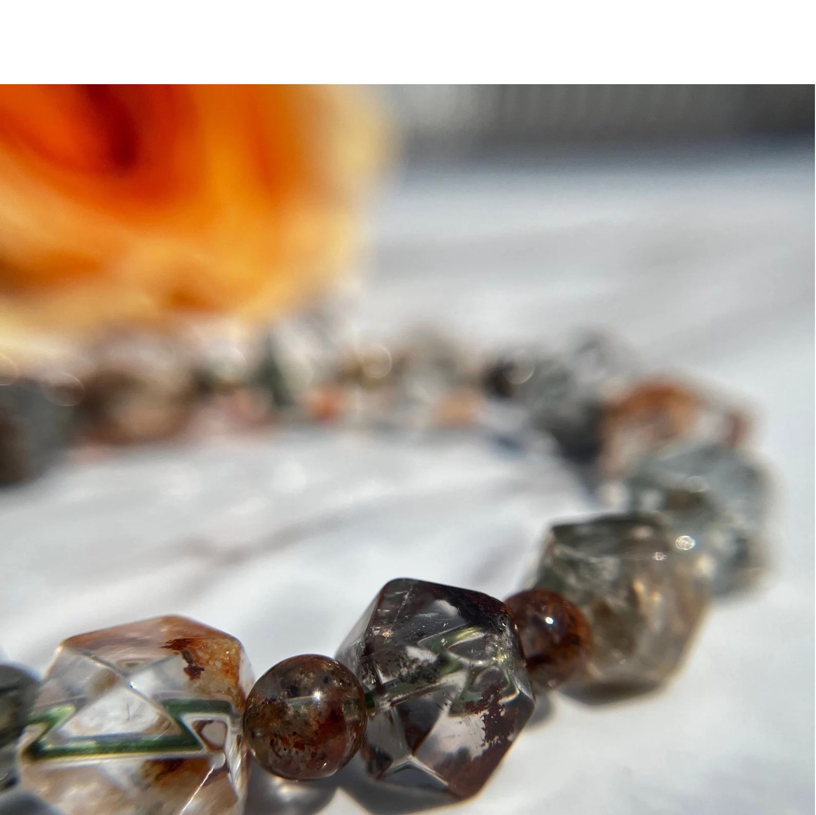 A bracelet is on a table next to a rose