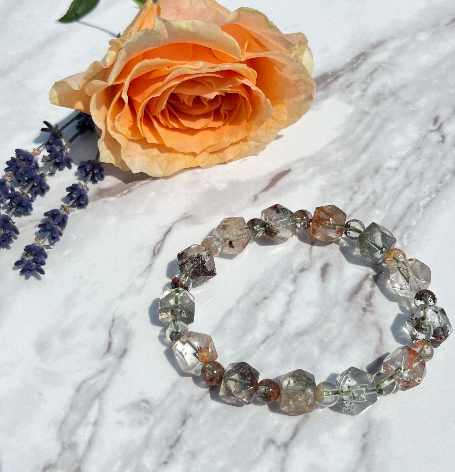 A bracelet is on a table next to a rose