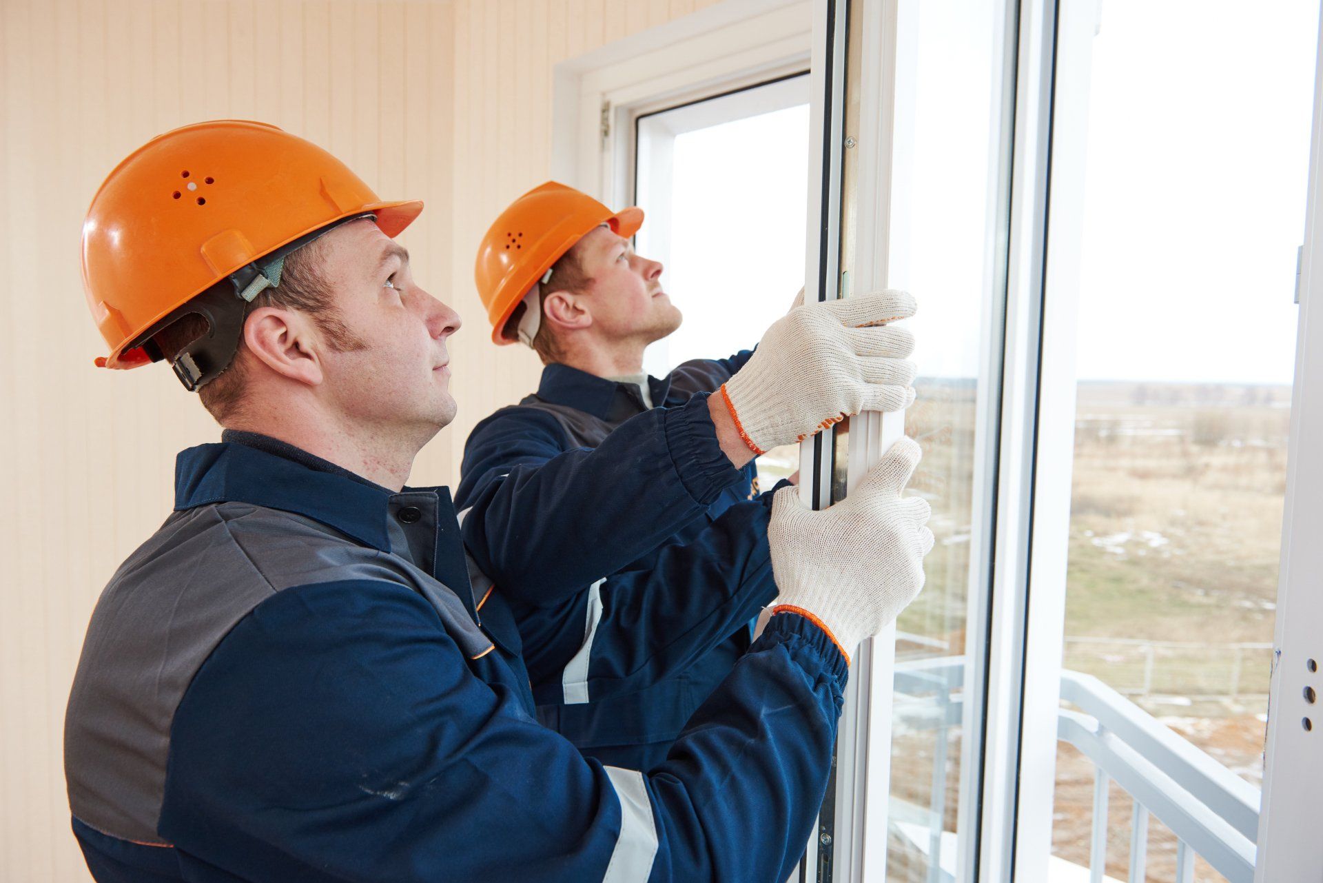 Two Construction Workers Are Installing a Window in a House — Headlands Glass in Ballina, NSW