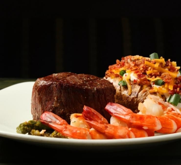 A white plate topped with steak shrimp and vegetables