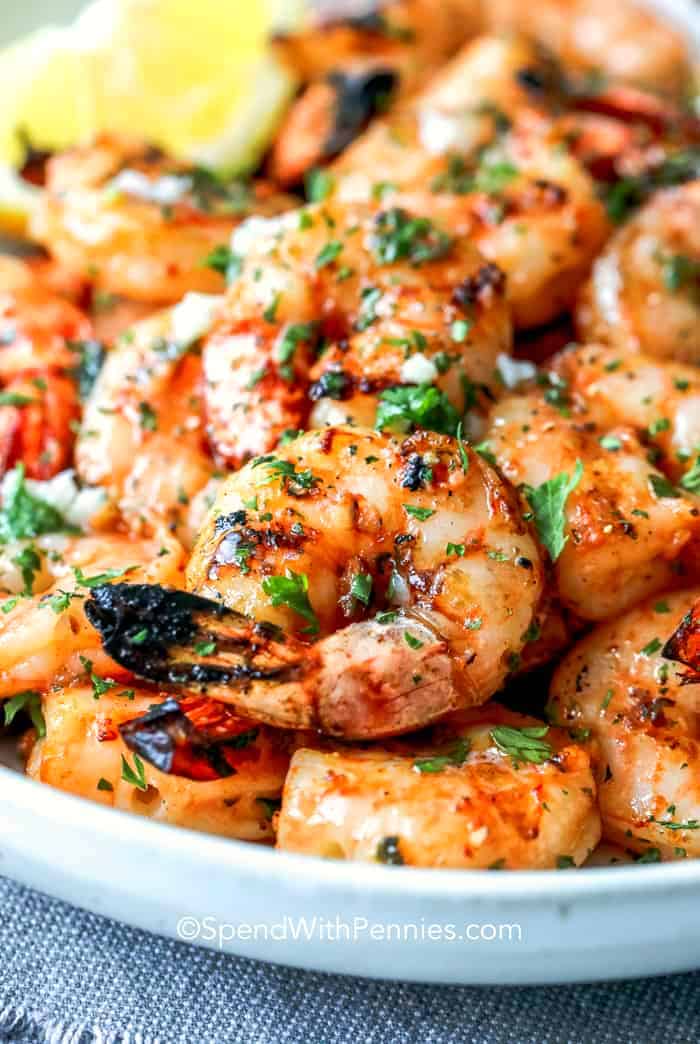 A white plate topped with grilled shrimp and tomatoes.