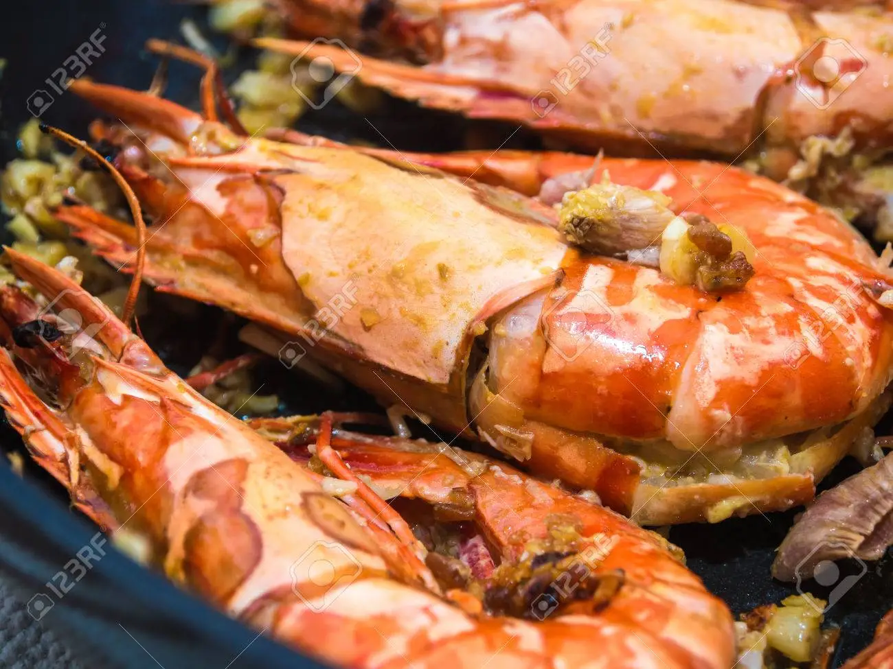 A close up of cooked shrimp in a pan.