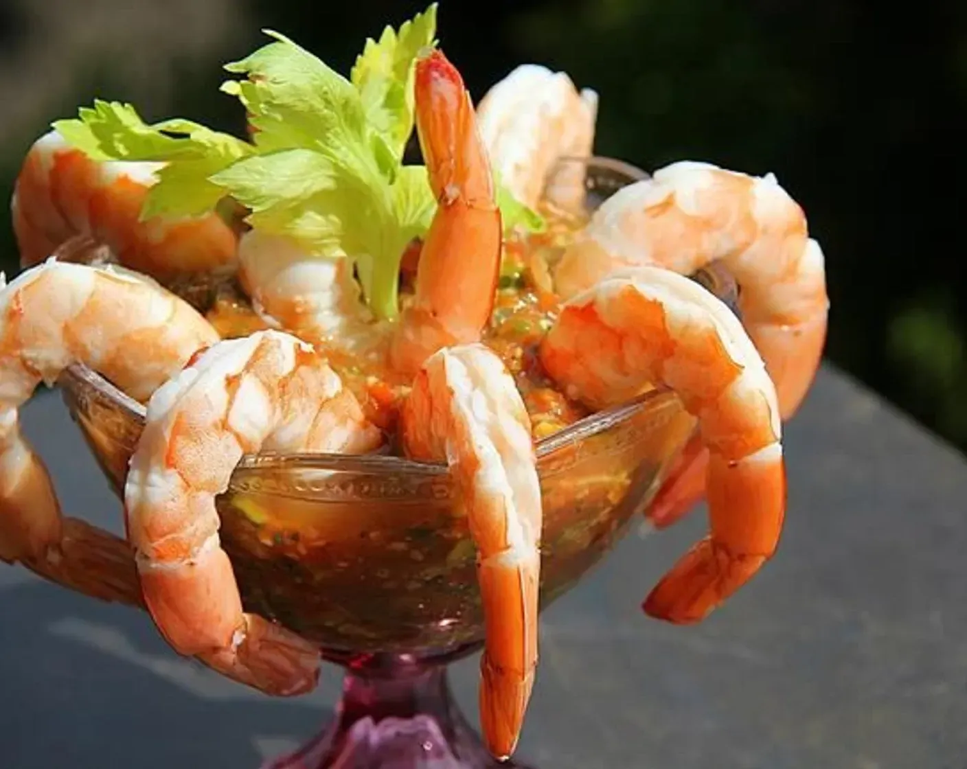 A glass bowl filled with shrimp and celery on a table