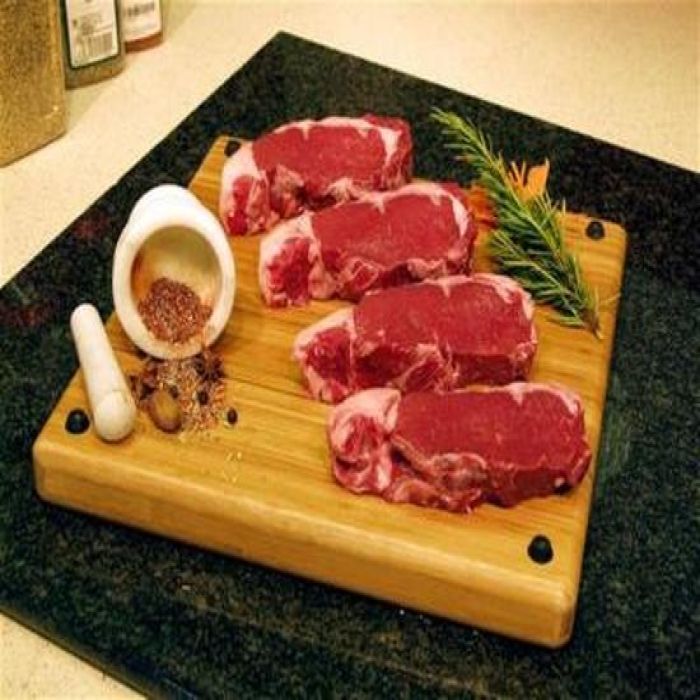 A wooden cutting board with meat and spices on it