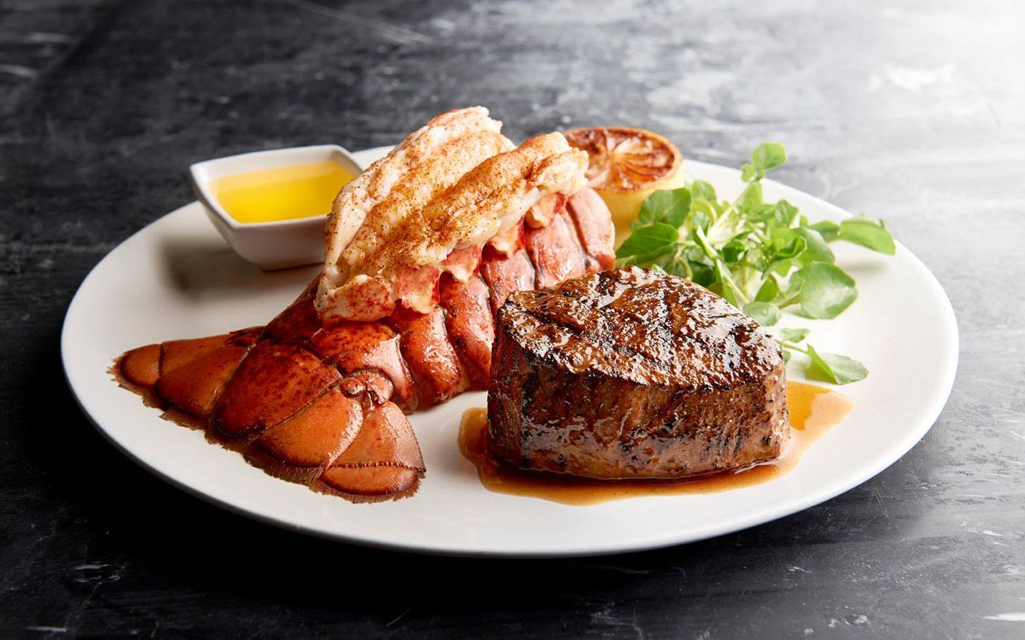 A white plate topped with a steak and lobster tail.