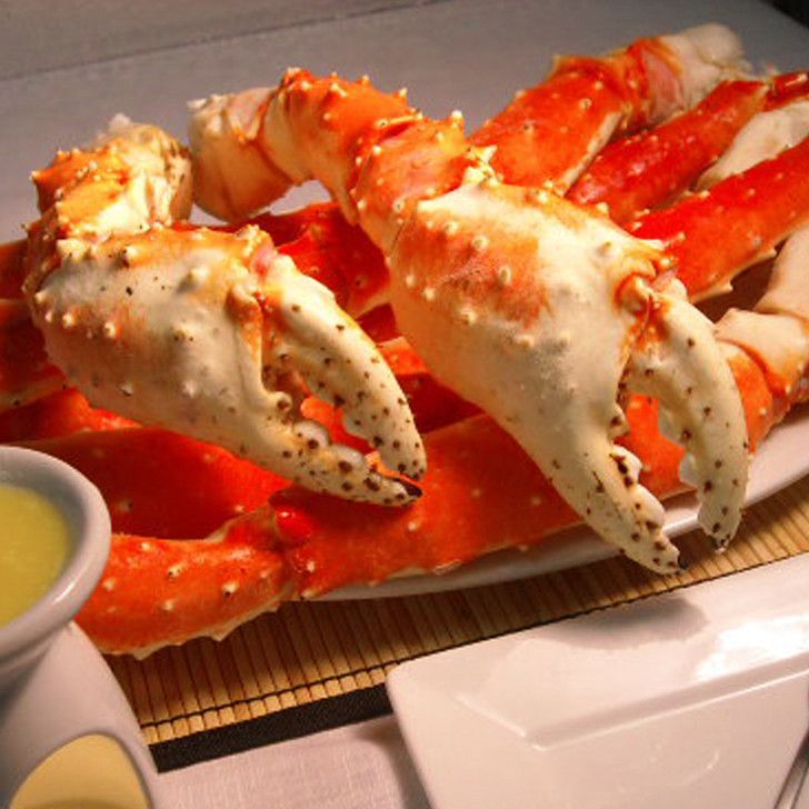 A plate of crab legs with sauce on the side