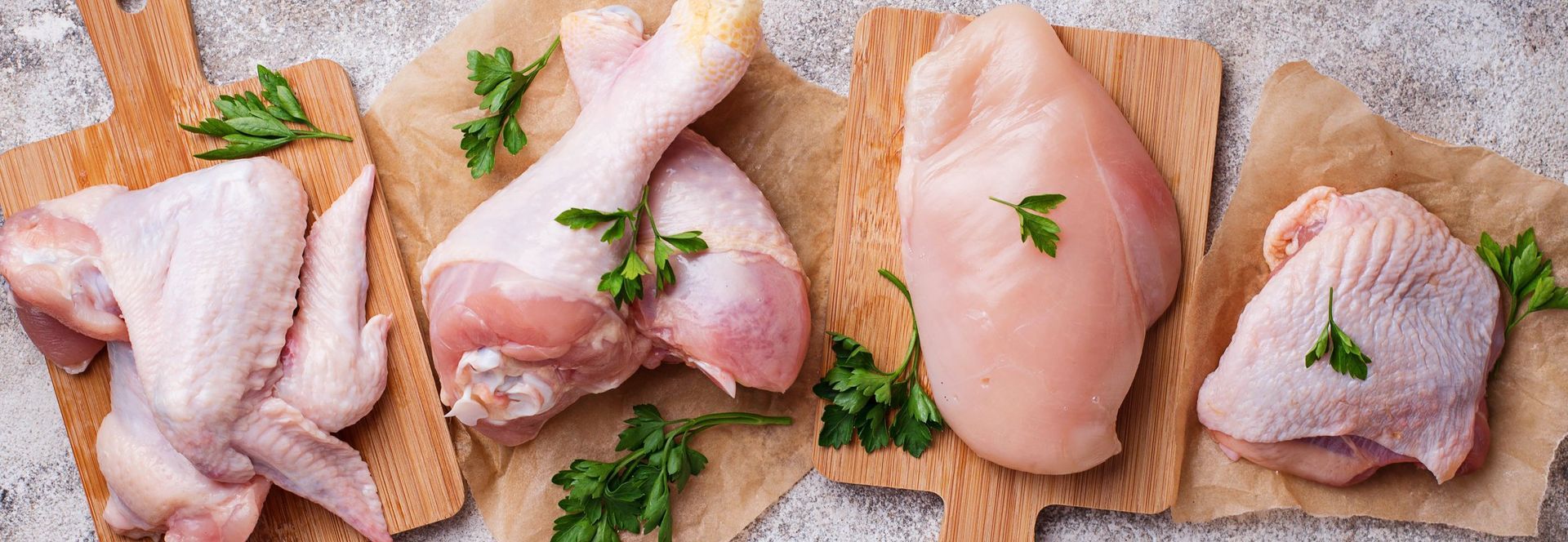 Raw chicken breasts , wings , legs and thighs on a wooden cutting board.