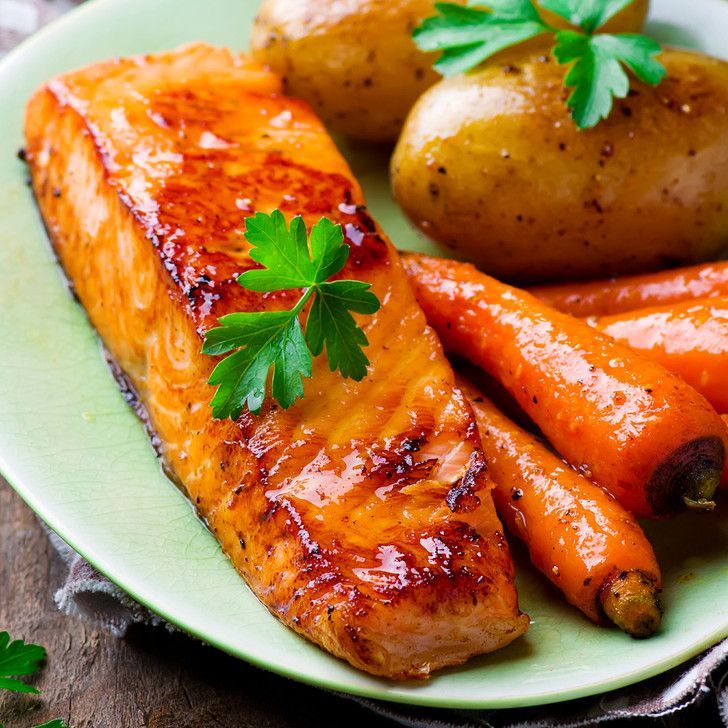 A green plate topped with salmon potatoes and carrots