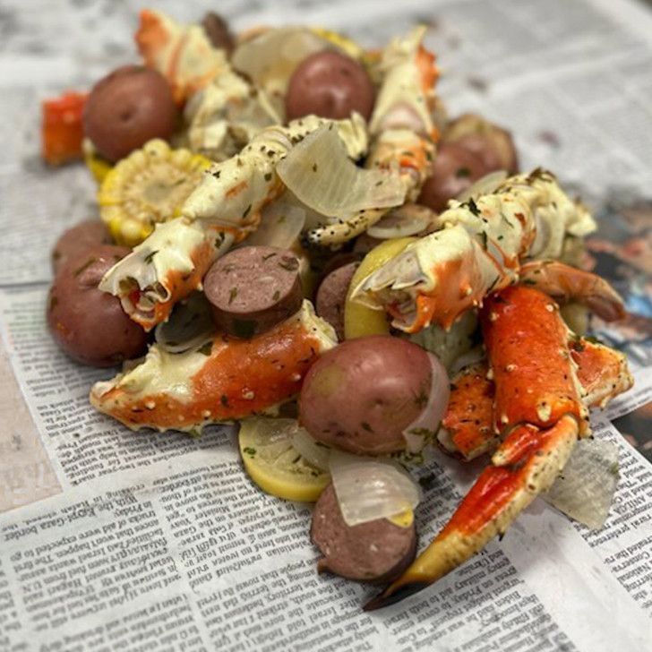 A pile of crab legs and potatoes on top of a newspaper