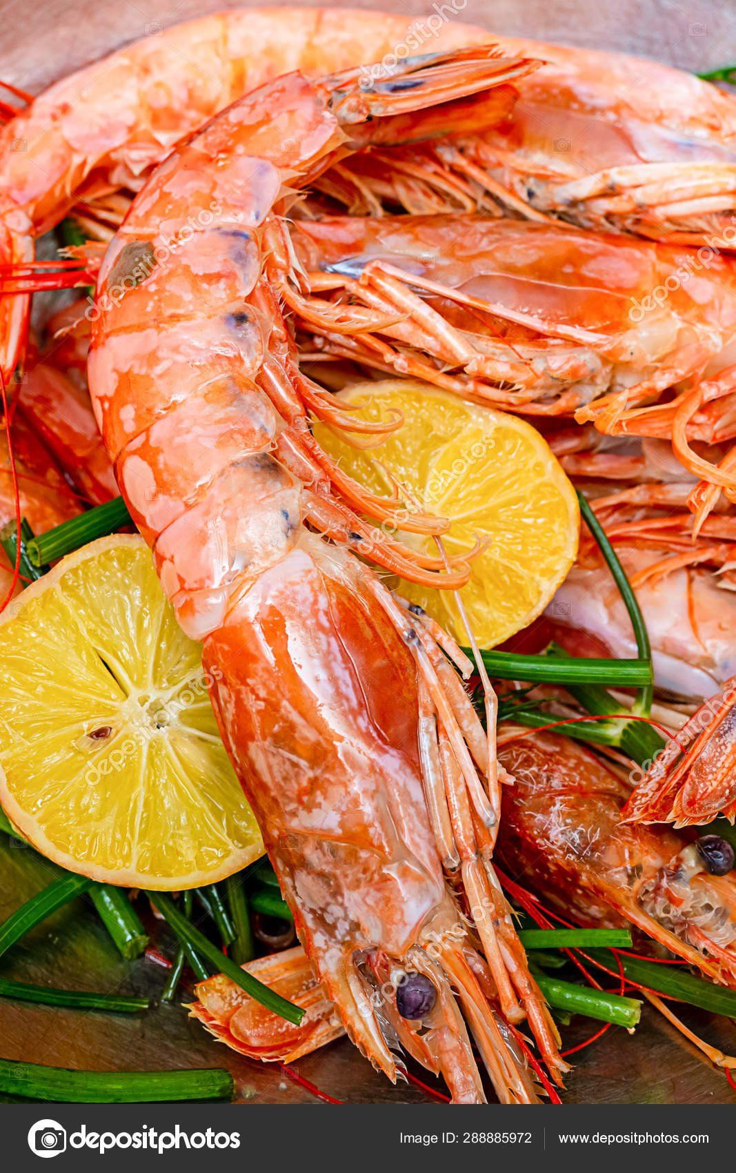 A close up of a plate of shrimp with lemon slices and green beans.