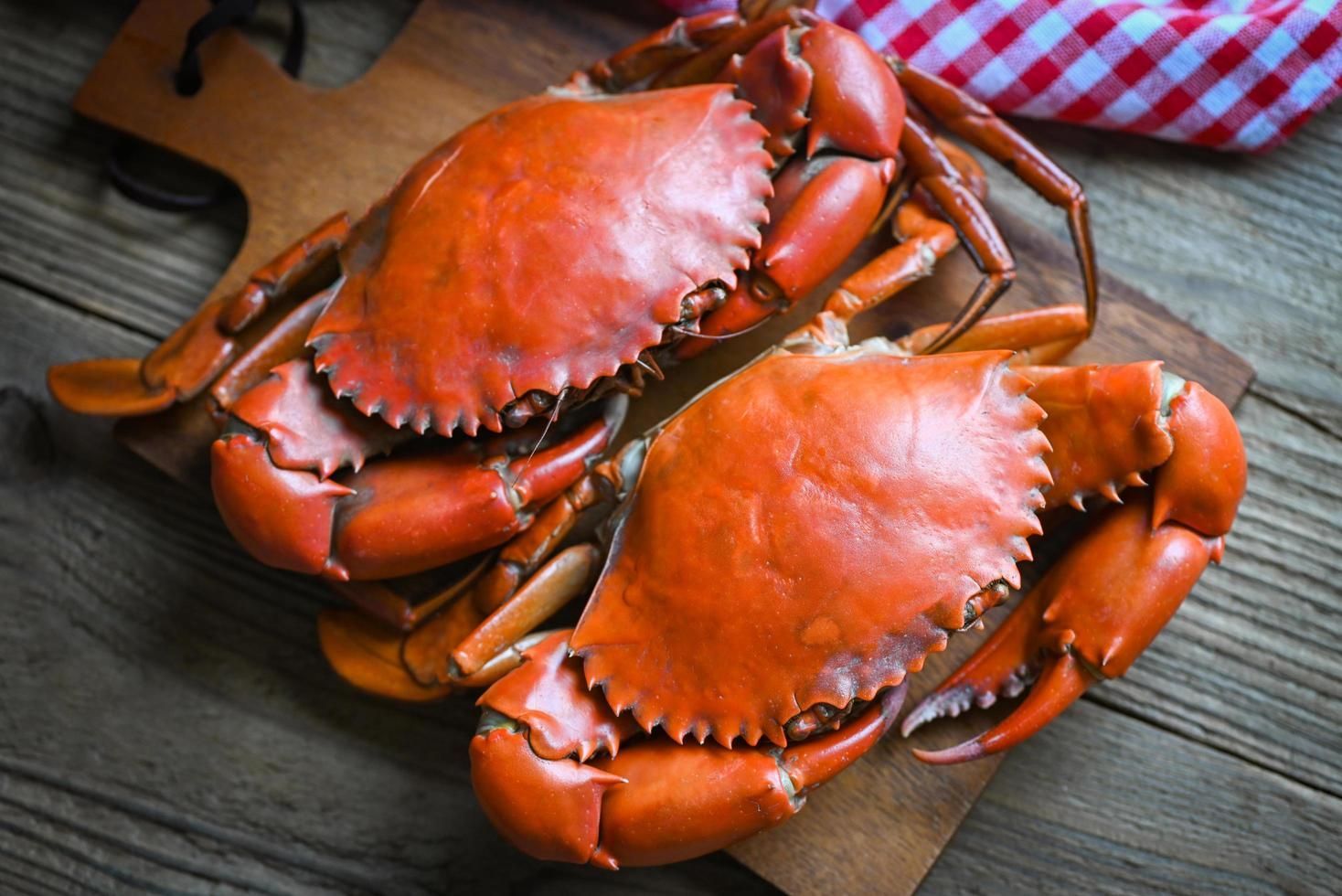 Two cooked crabs are sitting on a wooden cutting board.