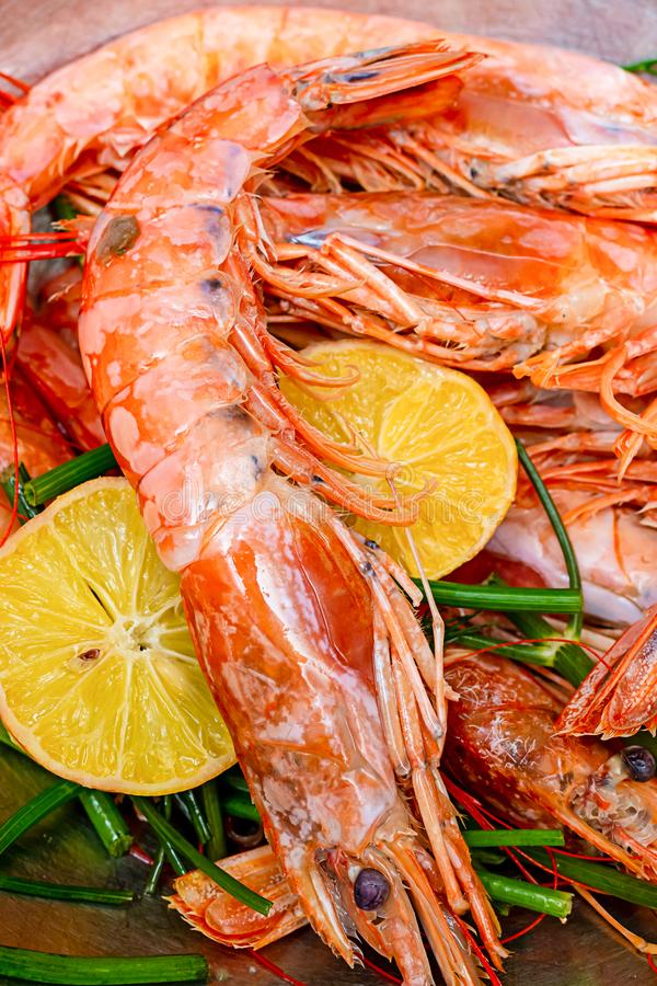 A close up of a plate of shrimp with lemon slices and green beans.