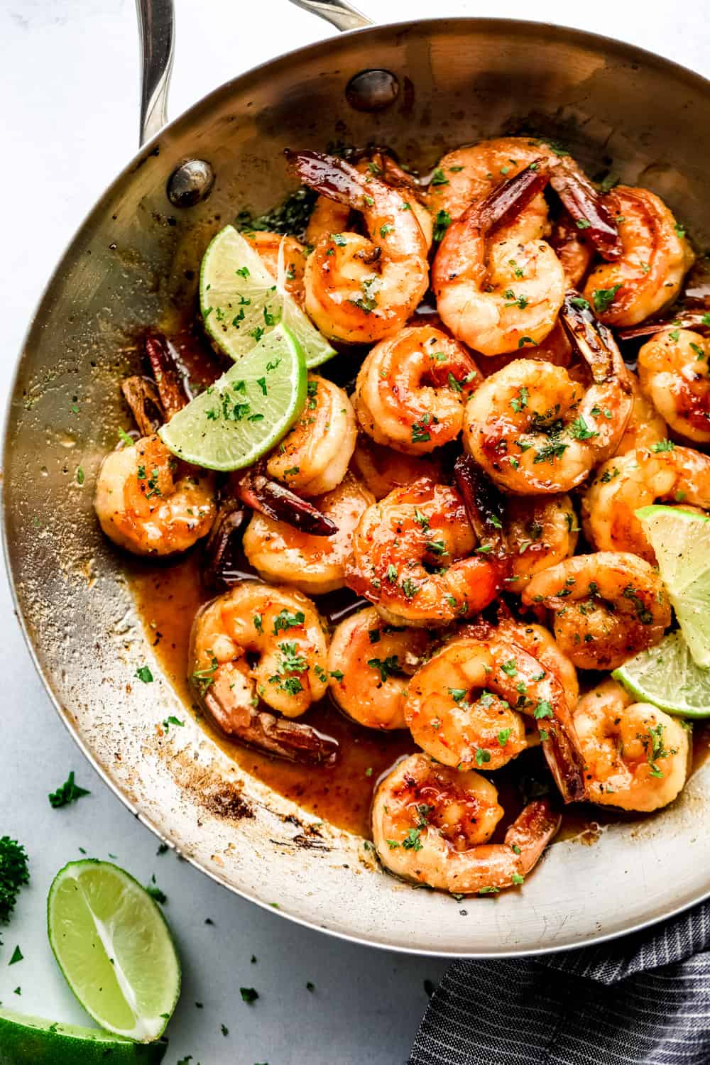 A pan filled with shrimp and lime wedges on a table.