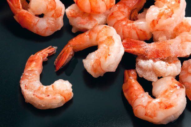 A close up of cooked shrimp on a black plate.