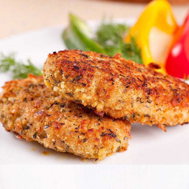 Two fried chicken patties on a white plate with vegetables