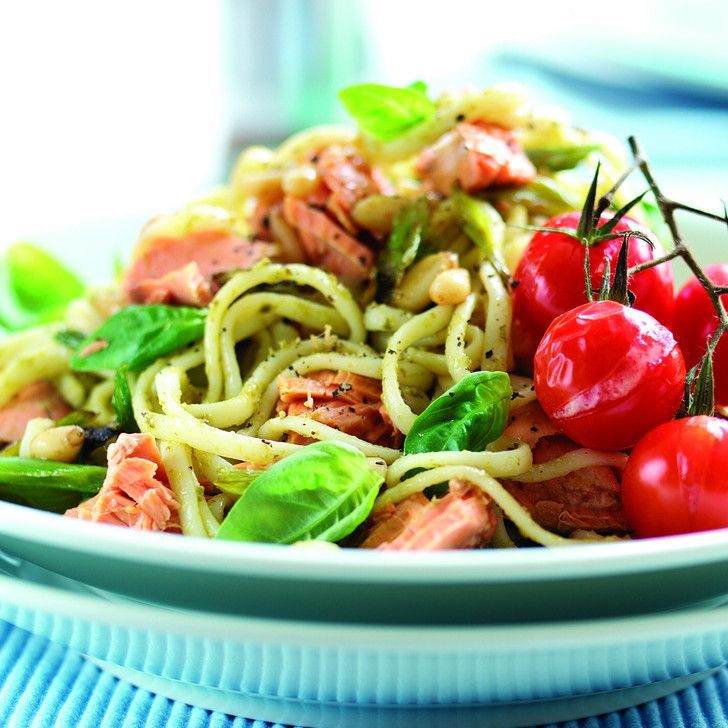 A plate of pasta with tomatoes and basil on a table.