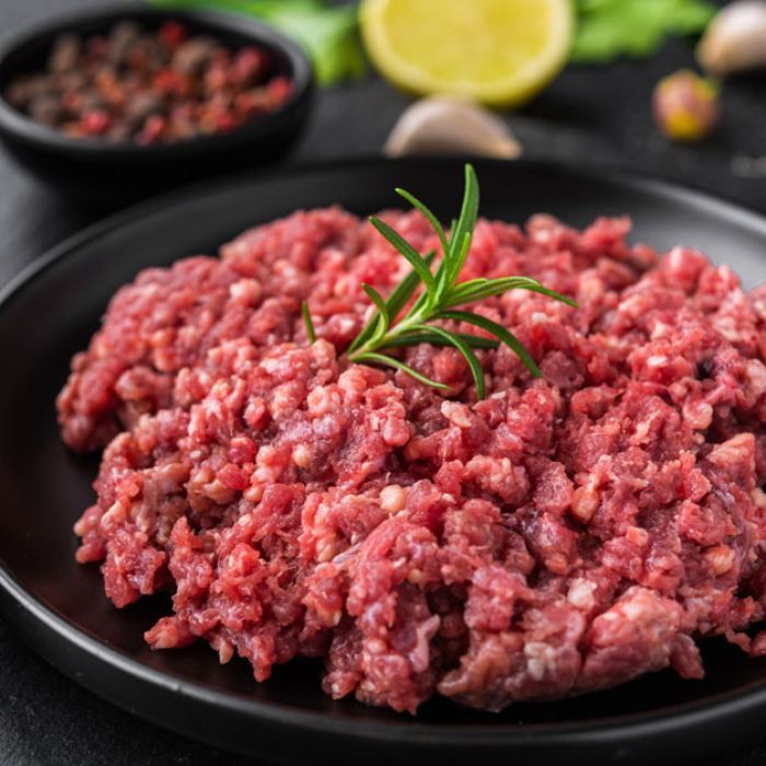 A black plate topped with ground beef and a sprig of rosemary.