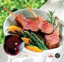 A plate of lamb chops and vegetables next to a glass of wine.