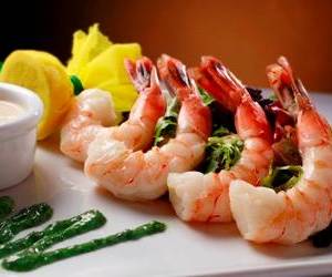 A white plate topped with shrimp and green sauce.
