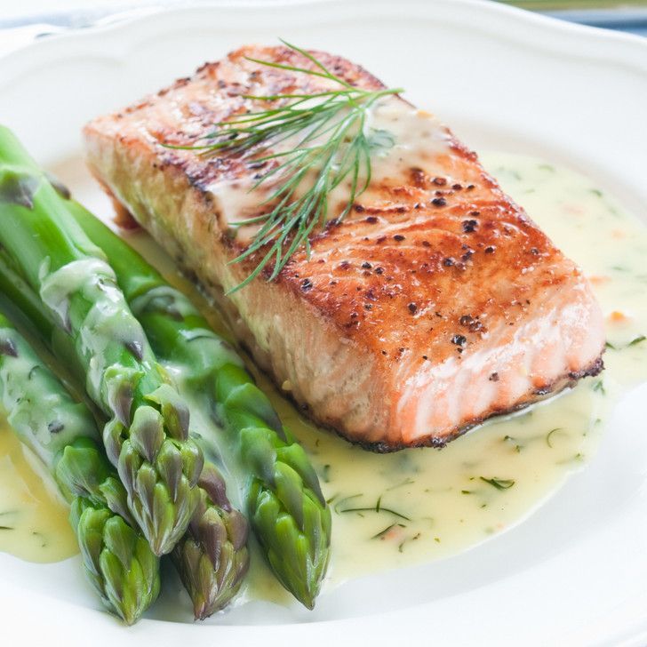 A white plate topped with asparagus and a piece of salmon
