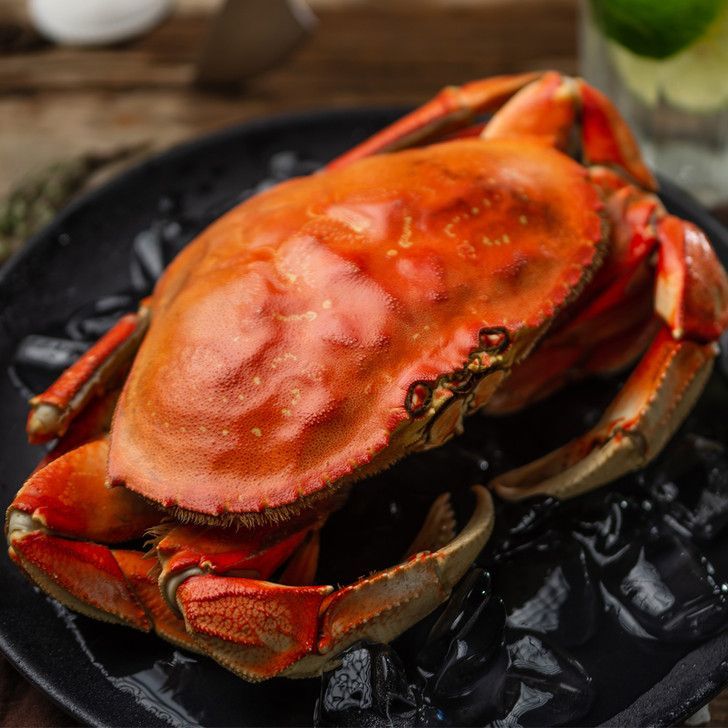 A crab is sitting on a black plate on a table.