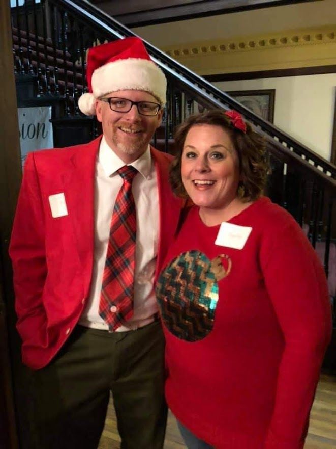 A man in a santa hat and a woman in a red sweater pose for a picture