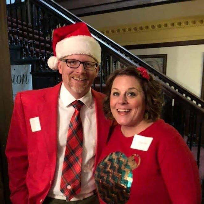 A man in a santa hat and a woman in a red sweater pose for a picture