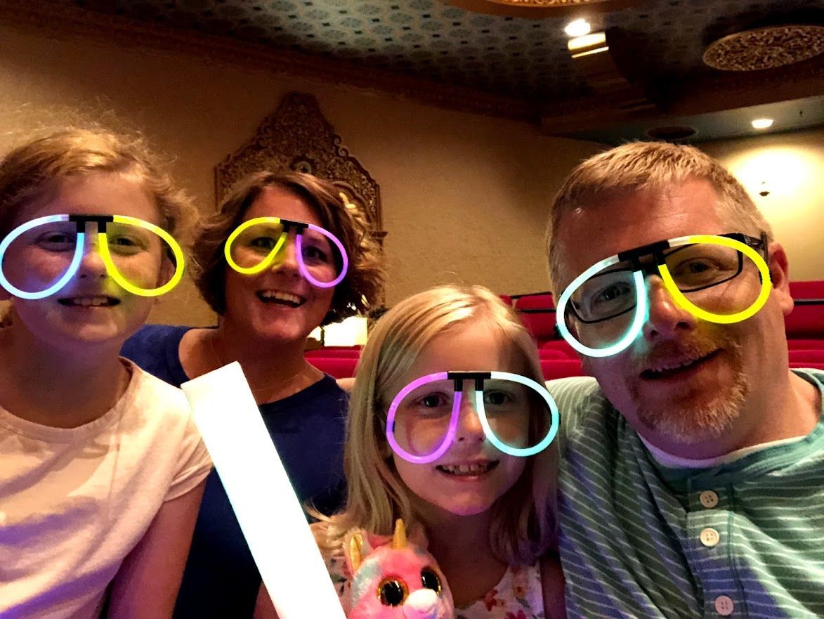 A man and two girls wearing glow in the dark glasses