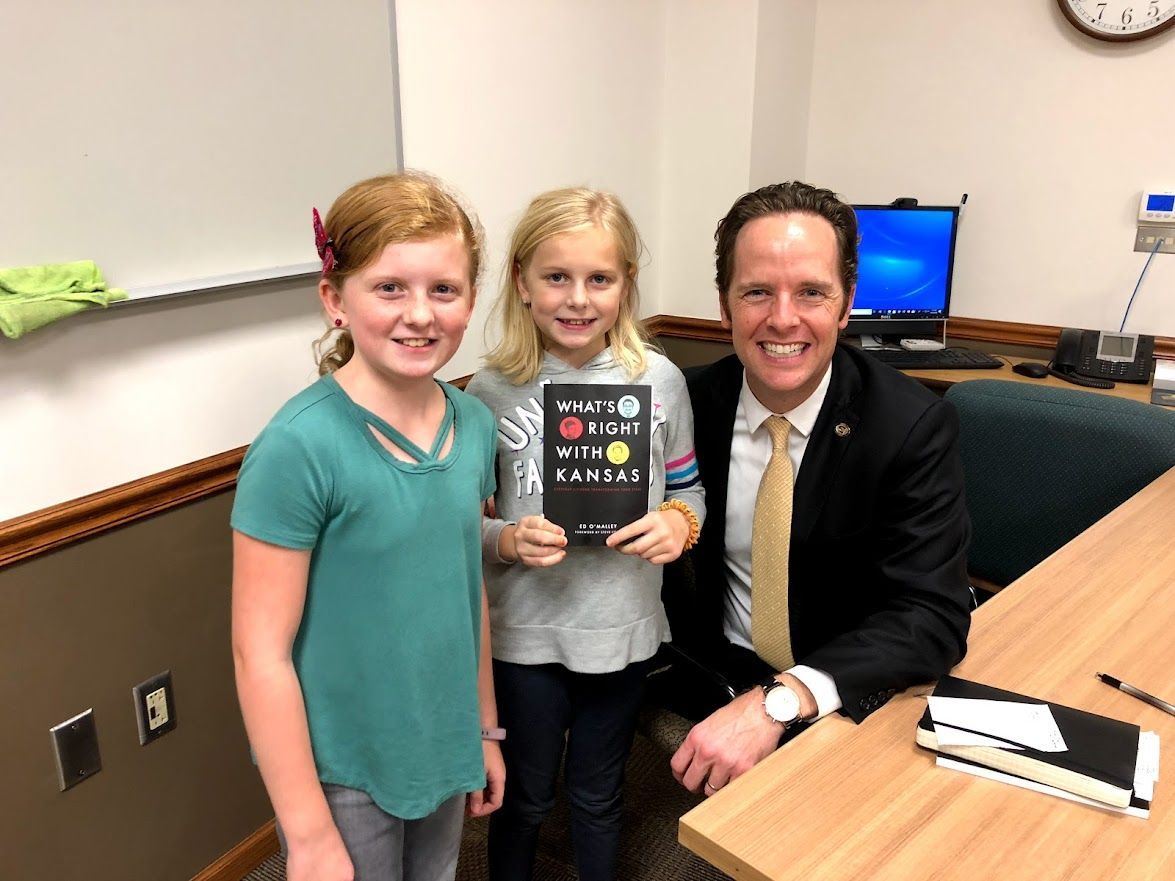 A man and two girls are standing next to each other holding a book.