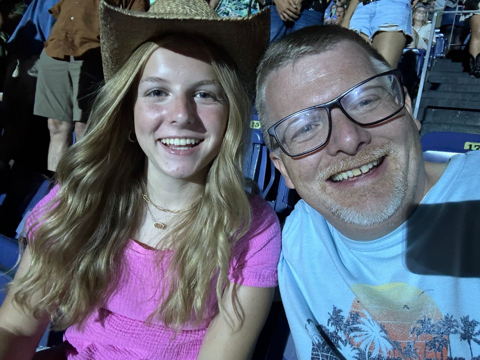 A man and a girl are posing for a picture in a concert stadium.
