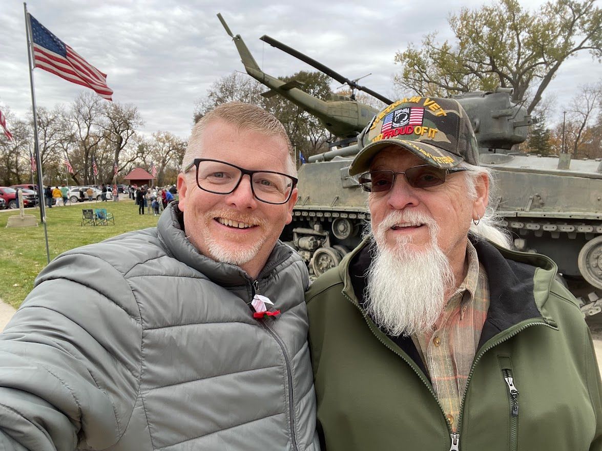 Two men are posing for a picture in front of a tank.