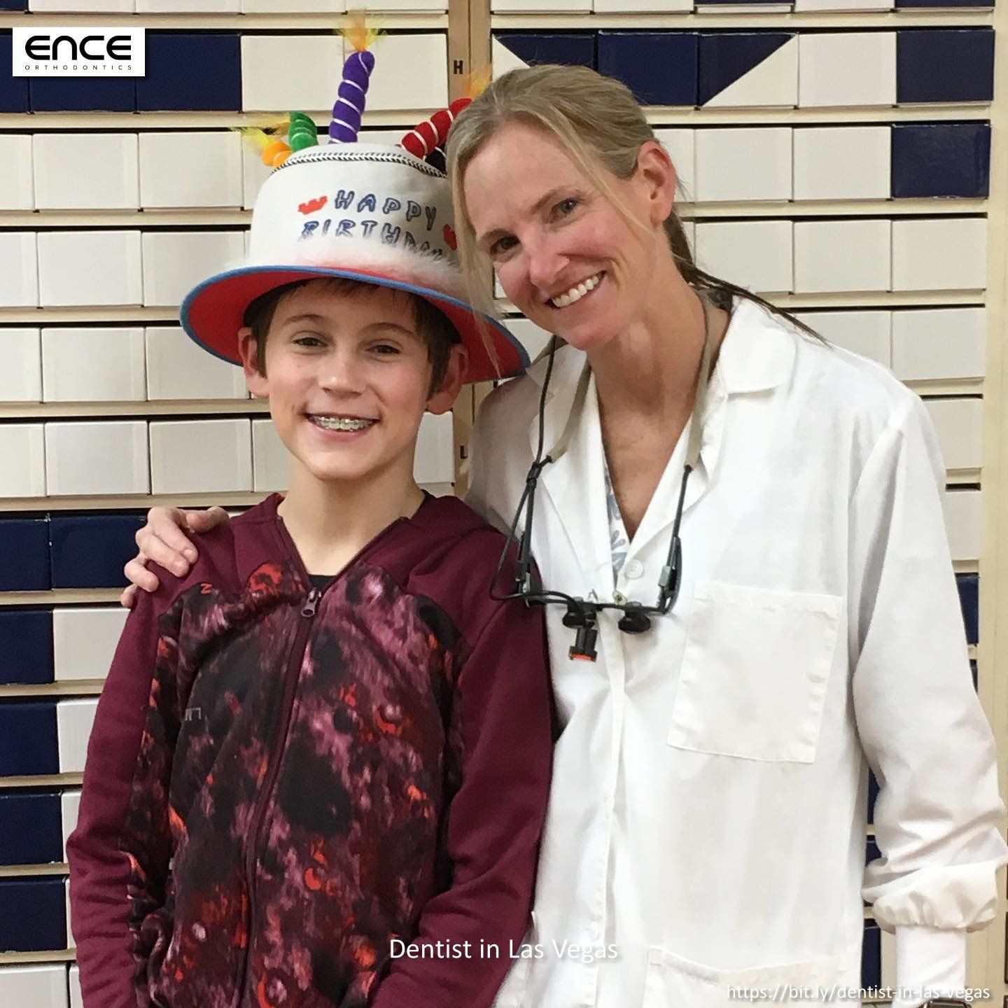 A woman in a lab coat stands next to a boy wearing a birthday hat