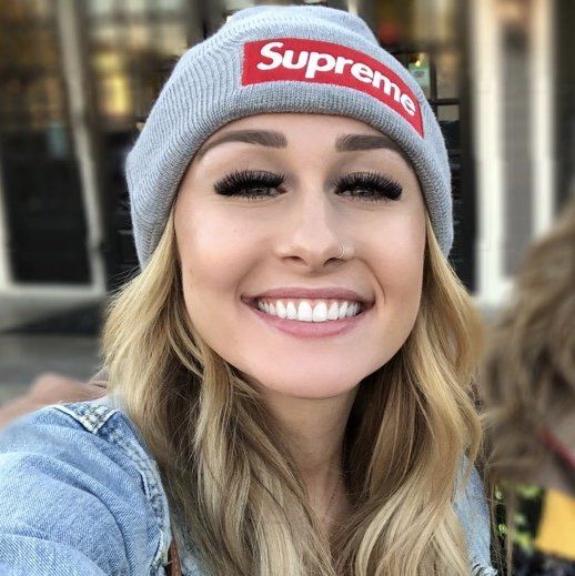 A woman wearing a supreme beanie smiles for the camera