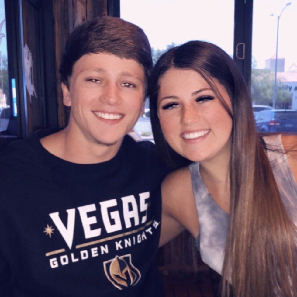 A man and a woman are posing for a picture and the man is wearing a vegas golden knight shirt