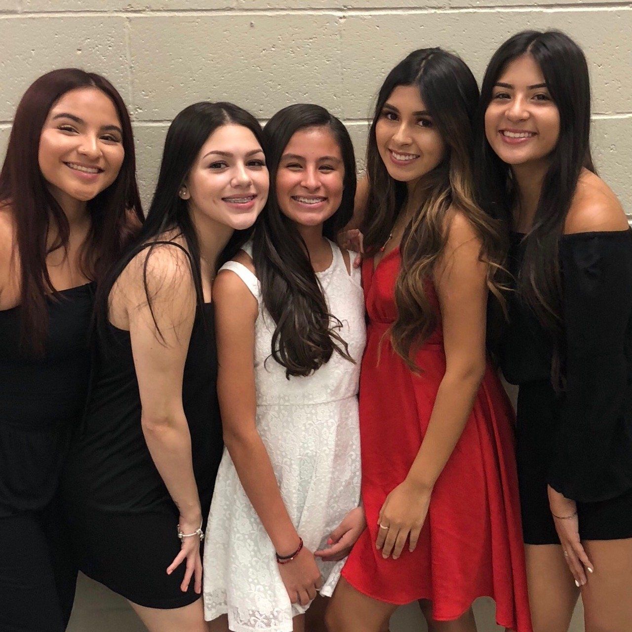 A group of women are posing for a picture and one of them is wearing a red dress
